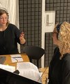 Two women speaking in a podcast studio.