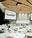 Large conference room with white upholstery with three large screens with "socialism", "flexicurity" and "democratic" on them.